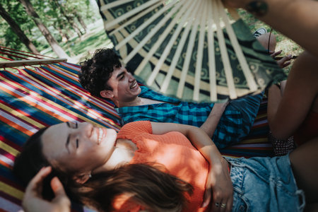 Friends relaxing on hammock during sunny day in park, enjoying leisure timeの写真素材