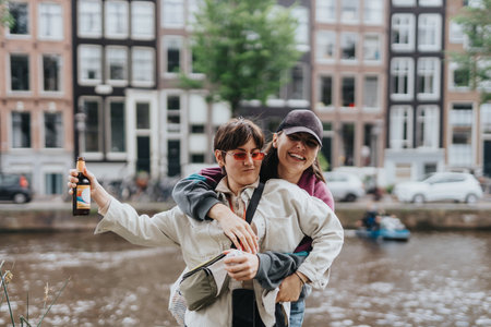 Happy lesbian couple hugging and smiling by a canal in Amsterdam, enjoying a lovely day outdoorsの写真素材