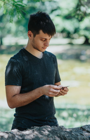 Young man using his smart phone in a peaceful park settingの写真素材