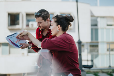 Business colleagues discussing marketing report outdoors in cityの写真素材
