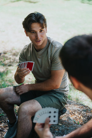 Friends enjoying a card game outdoors in a sunny parkの写真素材