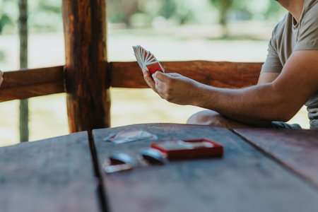 Friends playing cards at a rustic outdoor picnic tableの写真素材
