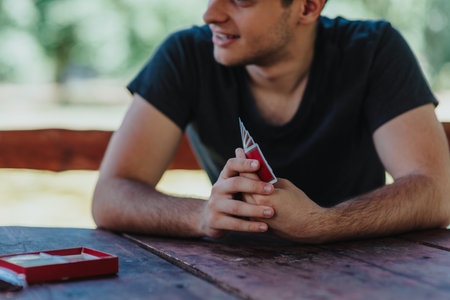 Young man playing cards at an outdoor picnic tableの写真素材