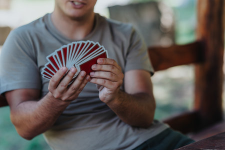 Man holding playing cards in a relaxed outdoor settingの写真素材