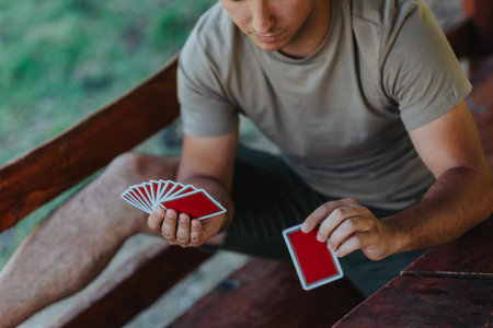 Man skillfully playing cards at an outdoor wooden tableの写真素材