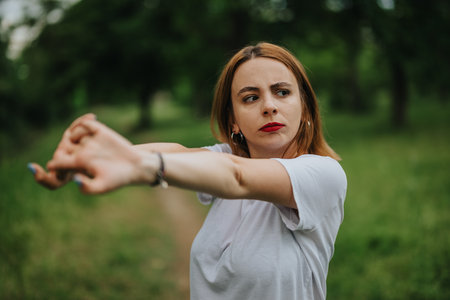Woman stretching arms in a green park with focus and determinationの写真素材