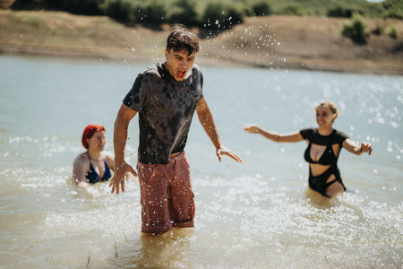 Friends splashing water and having fun at a lake during a summer dayの写真素材