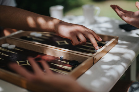 Hands playing an intense game of backgammon outdoors, capturing a moment of leisure and strategy...
