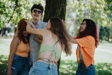 Friends laughing and messing each others hair up in a park settingの写真素材