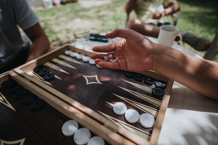 Friends enjoying a game of backgammon outdoors on a sunny dayの写真素材