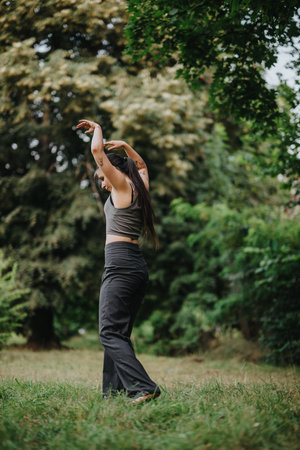 Woman dancing freely in a lush green forest setting outdoorsの写真素材