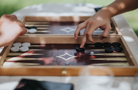 Hands playing backgammon outdoors on a sunny day for relaxationの写真素材