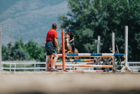 Equestrian riding session with trainer giving instructions near jumping hurdlesの写真素材