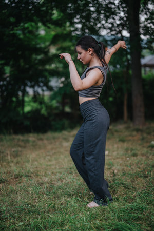Woman practicing yoga in the park surrounded by nature and treesの写真素材