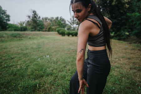 Young woman dancing gracefully in a green park, expressing freedom and movement through contemporary dance on a serene dayの写真素材