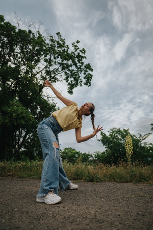 Young woman dancing outdoors in casual clothes enjoying natureの写真素材