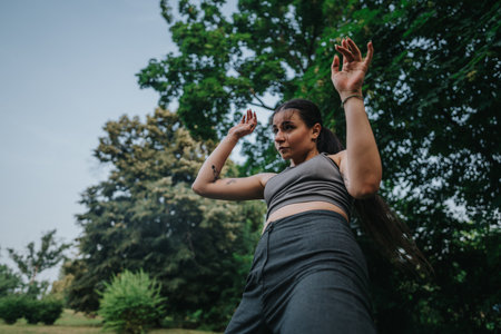 Young woman dancing with energy and grace in a vibrant green park, expressing freedom and joy in...
