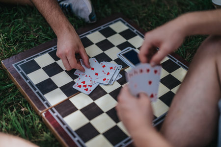 Group playing cards on a chessboard outdoors in casual settingの写真素材