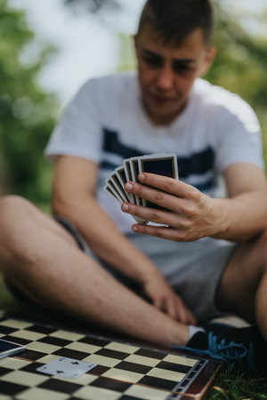 Young man strategizing card game move on sunny dayの写真素材