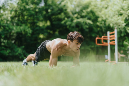 Fit man exercising in nature doing push-ups on grass in an outdoor parkの写真素材