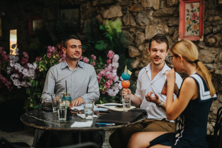 Friends enjoying a casual outdoor meeting at a charming cafeの写真素材