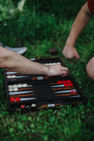 Friends playing backgammon outdoors on a grass field in summertimeの写真素材