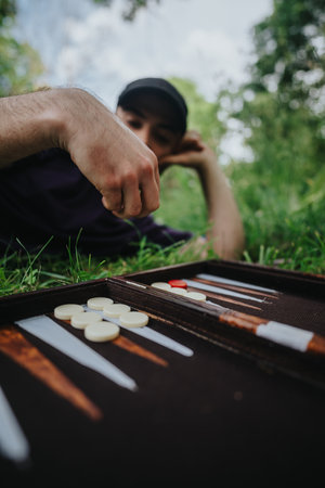 Young man playing backgammon outdoors in a relaxed summer settingの写真素材