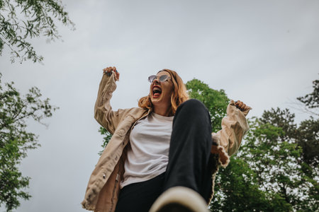 Joyful woman celebrating in nature with arms raised and smileの写真素材