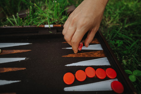 Close-up of hand playing backgammon outdoors on grassy surfaceの写真素材