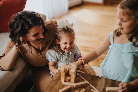 Mother and daughters playing with wooden blocks at homeの写真素材