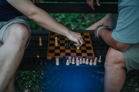 Two people playing chess on a wooden board outdoors