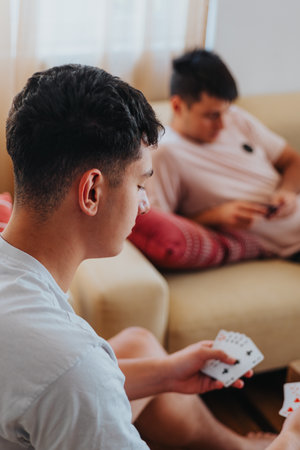 Family members having fun playing cards at home togetherの写真素材