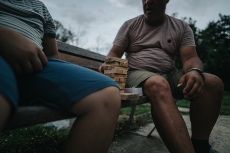 Father and son playing wooden block game on a park benchの写真素材