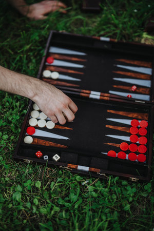 Hand playing backgammon outdoors on grass with dice and piecesの写真素材