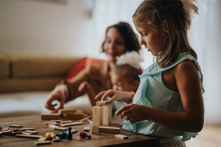 Mother and daughters playing with wooden blocks at homeの写真素材