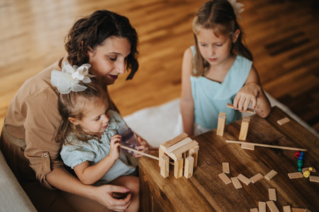 Mother and daughters playing with wooden blocks at homeの写真素材
