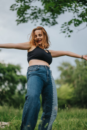 Joyful woman dancing freely in nature wearing casual attireの写真素材