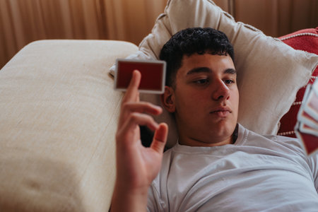 Young boy relaxing on couch playing a card game with friendsの写真素材