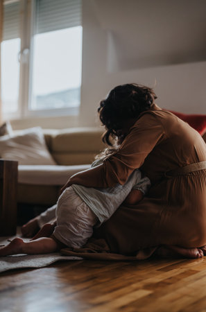 Mother embracing daughter in cozy home setting with loveの写真素材
