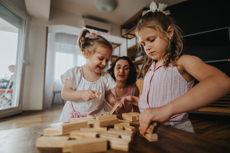 Happy family time with mother and daughters playing with wooden blocks at homeの写真素材
