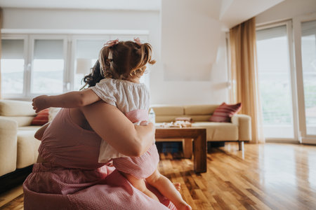 Mother and daughters sharing a tender embrace in a cozy living roomの写真素材