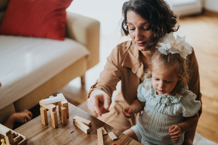 Mother and daughter playing with wooden blocks at homeの写真素材