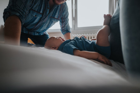 Father playing with baby on bed at home in daylightの写真素材