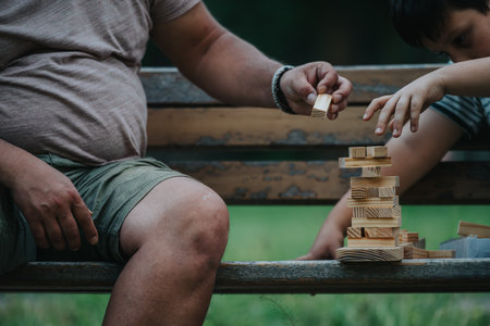 Father and son playing with wooden blocks in a park settingの写真素材