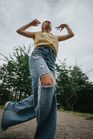 Low angle view of a woman in ripped jeans and yellow shirt walking outdoors