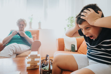 Grandmother knitting while grandson plays with blocks at homeの写真素材