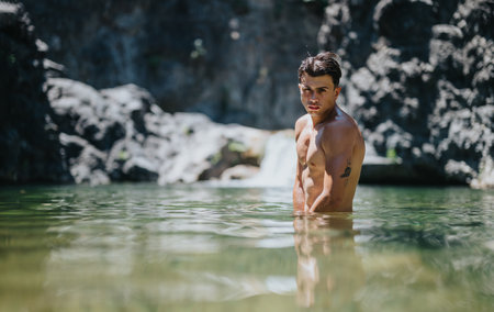 Young man enjoying a refreshing swim in a natural outdoor pool surrounded by rocks and tranquilityの写真素材