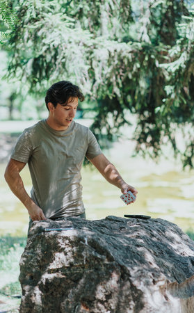 Young man performing card trick outdoors on sunny dayの写真素材