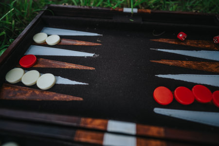 Backgammon board with red and white pieces in a garden settingの写真素材