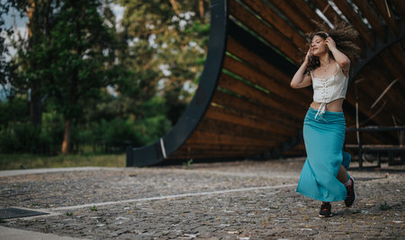 Young woman joyfully dancing in a sunny urban park settingの写真素材